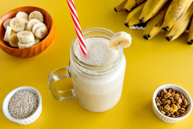 Banana smoothie cup healthy shake of banana with banana oatmeal and granola in the background