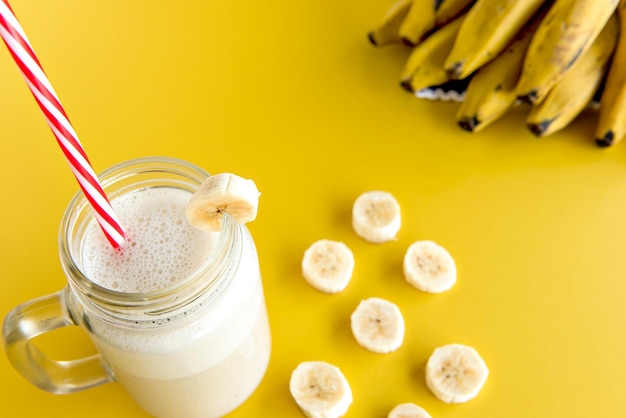 Banana smoothie cup healthy shake with banana slices in the background