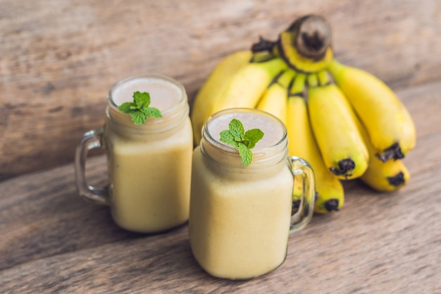 Banana smoothies and bananas on an old wooden background.