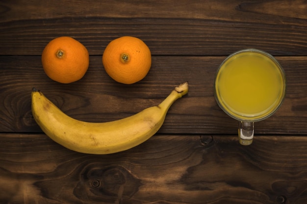 Banana tangerines and a glass of smoothies on a wooden background Minimal concept of plant nutrition