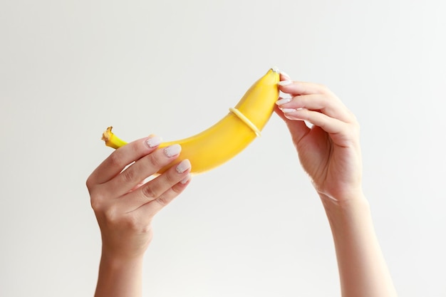 banana with a condom on a white background. sex education