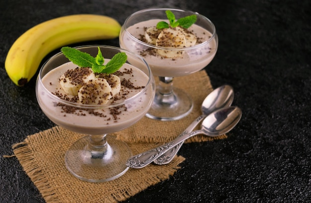 Banana yogurt with cinnamon and granola in glasses.