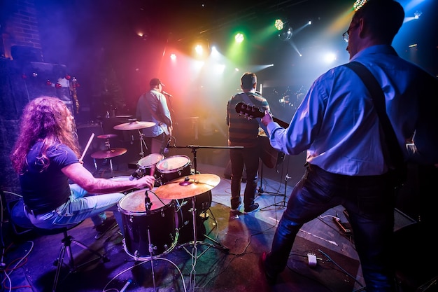 Band performs on stage, rock music concert in a nightclub. Authentic shooting with high iso in challenging lighting conditions. A little bit grain and blurred motion effects.