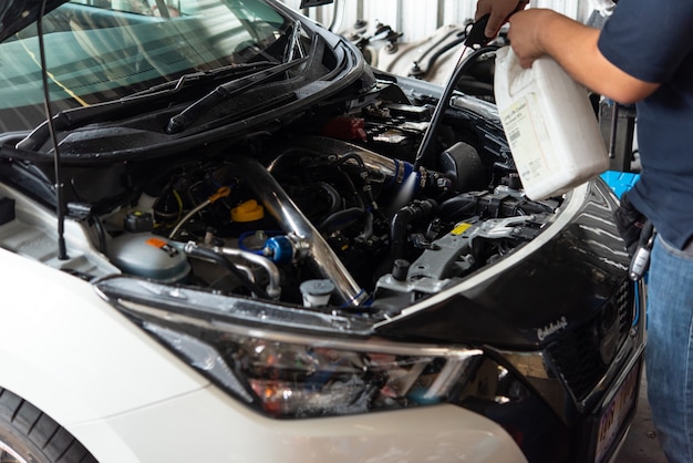 Bangkok, Thailand - April 4, 2020 : Unidentified car mechanic or serviceman cleaning the car engine after checking a car engine for fix and repair problem at car garage or repair shop