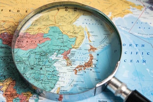 Bangkok Thailand January 20 2022 Japan Magnifying glass close up with colorful world map travel geography tourism and exploration concept