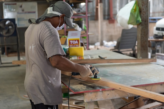 Bangkok, Thailand - May 1, 2020 : Unidentified carpenter build furniture or products from slat and timber wood from natural hardwood in warehouse or sawmill at wood factory for a construction or sale