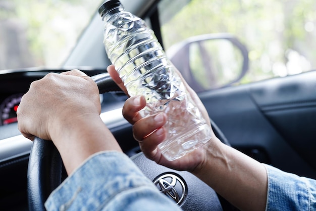 Bangkok Thailand May 15 2022 Asian woman driver hold cold water for drink in car dangerous and risk an accident