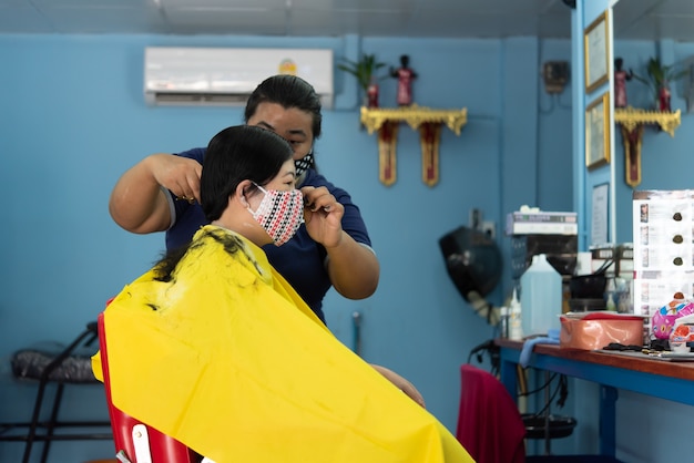 Bangkok, Thailand - May 16, 2020 : Unidentified asian woman hairdresser or hairstyle haircut a woman plump body customer in fashion hairstyle at barbershop