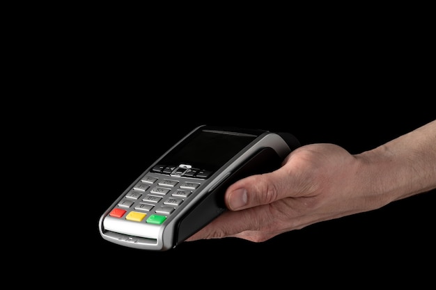 Bank terminal for payment by credit cards in hand on black background