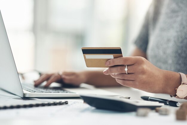 Banking payment and paying bills online with ebanking on a laptop with a credit or debit card Closeup of a woman doing online shopping during inflation Female making payment for debt and mortgage