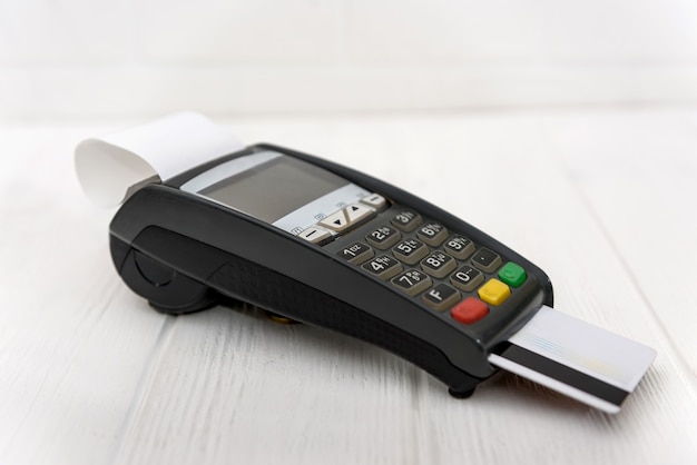 Banking terminal with credit card on wooden background