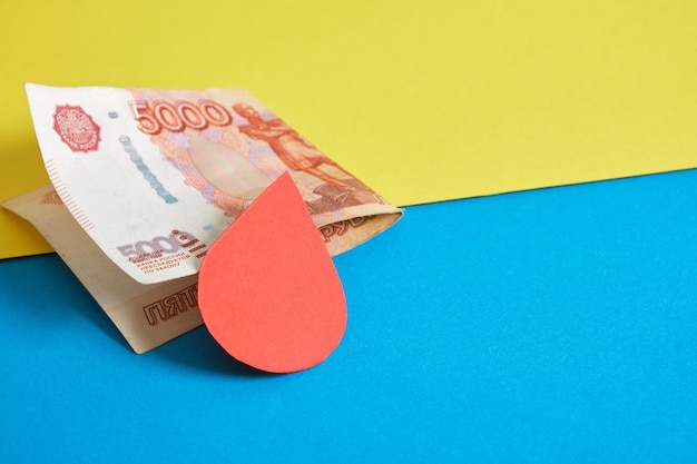 Banknote of 5000 rubles paper blood drop on ukrainian flag colors backgound