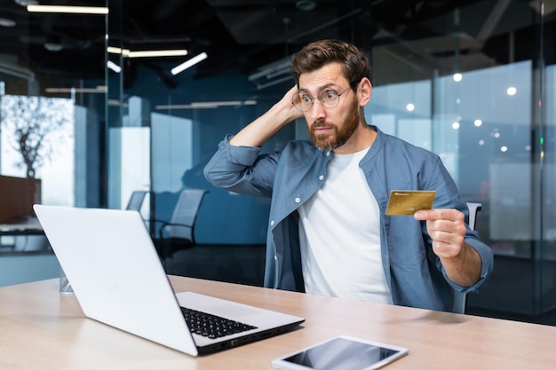 Bankruptcy financial problems unsuccessful online shopping shocked young man sitting in the office