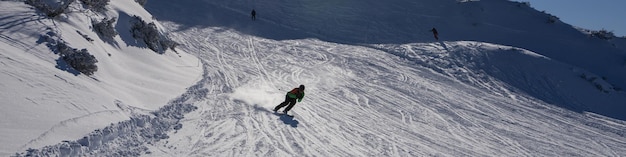 Banner 41 with a skier in a green suit racing down a mountain slope Mountain landscape with clear blue sky