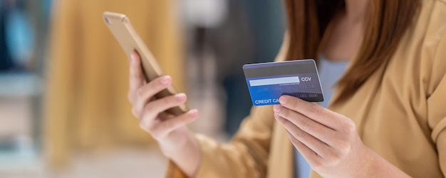 Banner of Asian woman using credit card with mobile phone for online shopping in department store