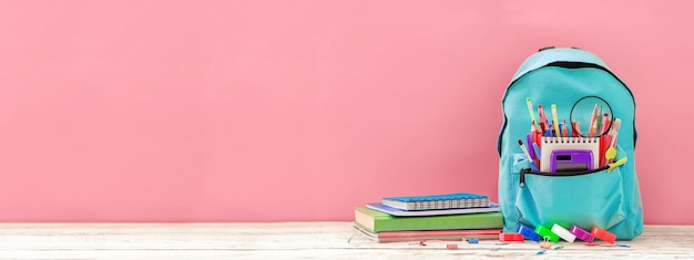 Banner Full turquoise School Backpack with stationery on table on pink Back to school concept