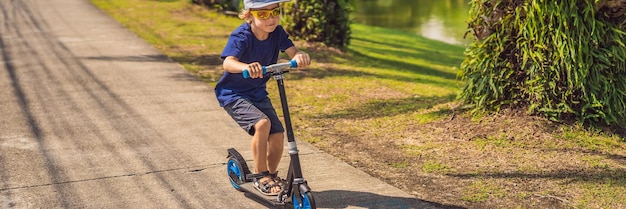 Banner long format child on kick scooter in park kids learn to skate roller board little boy skating