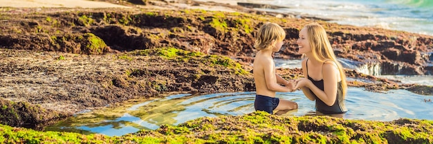 Banner long format mother and son tourists on pantai tegal wangi beach sitting in a bath of sea