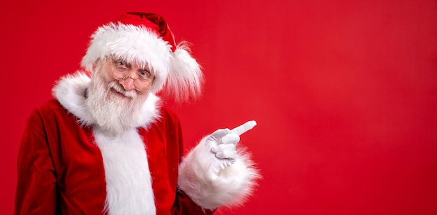 Banner santa claus pointing aside empty copy space on finger and looking showing blank place for