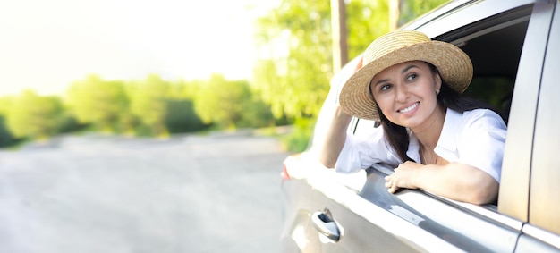 Banner Travel vacation A young beautiful woman in a hat sits in a car and smiles looking into the distance Lifestyle