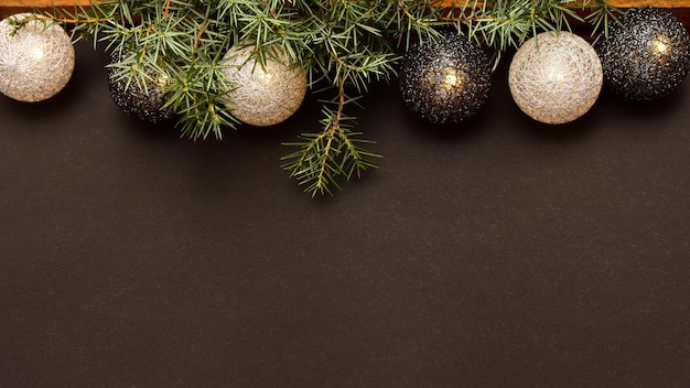 Banner with garland in the form of wicker balls on a dark background with a sprig of spruce.