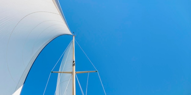 Banner with white main sail and genoa head sail of a sailing yacht in the wind sailing on the sea calm sunny weather