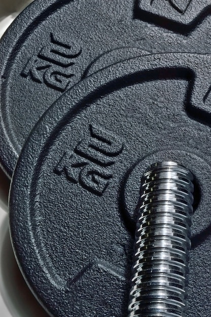 Photo bar and black discs of a collapsible dumbbell with weight designation. close-up.