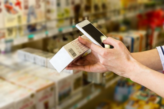 Bar code technology Female hands with a phone scan a barcode on a pack of tea in a supermarket