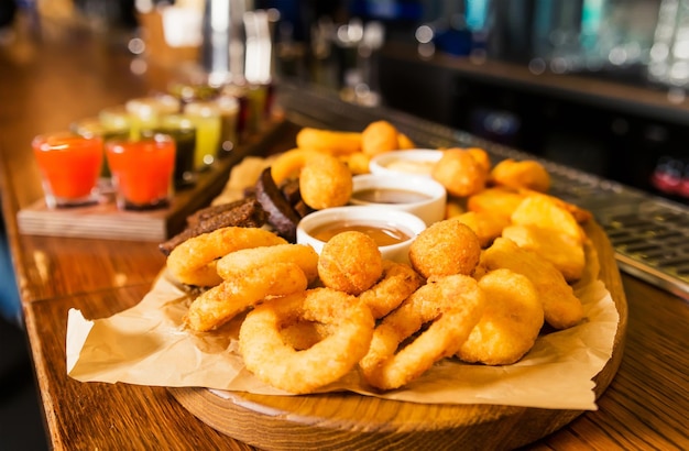 On the bar counter there is a set of various tinctures and a plate with snacks onion rings cheese sticks balls and croutons