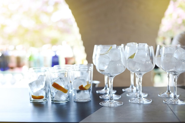 Bar counter with glasses and cups filled with ice and orange ready to serve in closeup mode