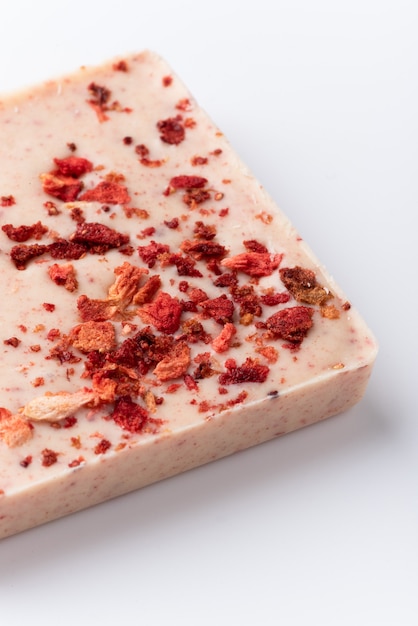 A bar of white chocolate with freeze-dried strawberries on a white background.