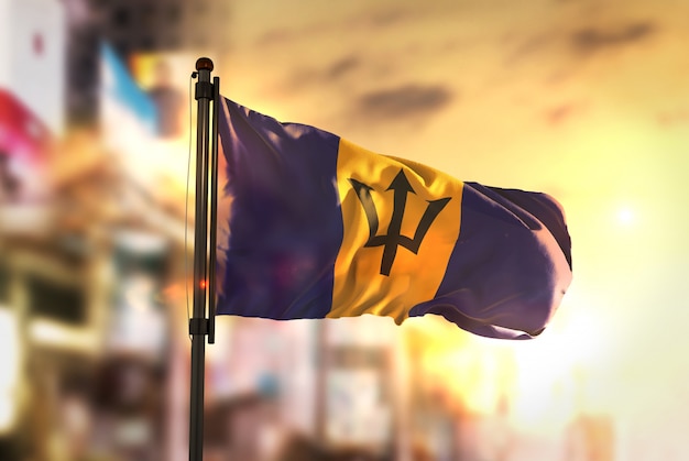 Barbados Flag Against City Blurred Background At Sunrise Backlight