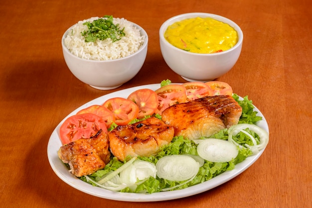 Barbecue fish filet accompanied by white rice fish mush and salad Traditional Brazilian appetizer