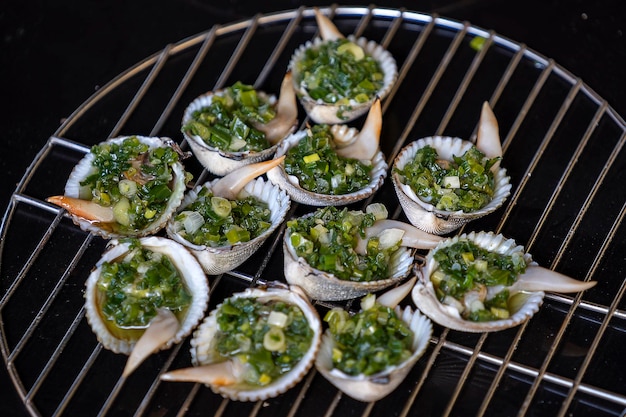 Barbecue grill cooking seafood grilling seashells with green onion Vietnam close up