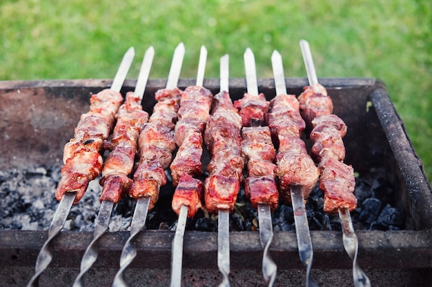 Barbecue on the grill. Kebab on skewers cooking outdoors. Cook shashlik on skewers in the fresh air.