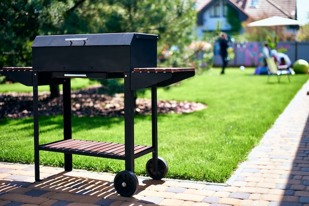 Barbecue grill on wheels with wooden stands in the garden