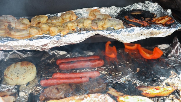 Barbecue grill with meat shrimp chicken vegetables and hand grilling food symbolizes festive out