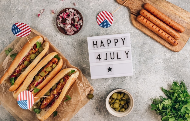 Barbecue grilled hot dog with pickled cucumber, red onion and mustard on stone background. Top view