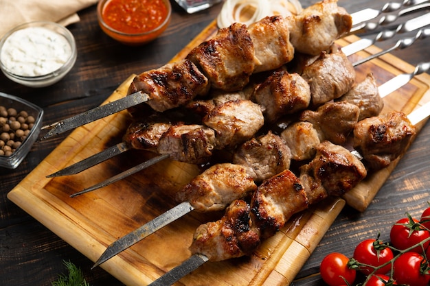 Barbecue Grilled pork shashlik kebabs meat on metal skewer on cutting board rustic style