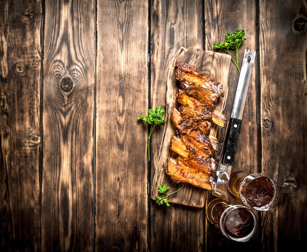 Barbecue ribs with a cold beer. On a wooden table.