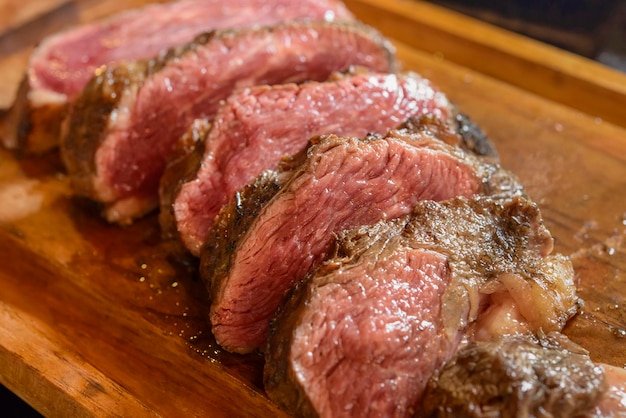 Barbecue of roasted and sliced meat on wooden board with blurred background Brazil