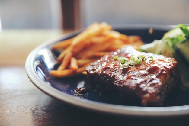 Barbecued pork ribs steak with fresh vegetables on an old rustic wooden in restaurant