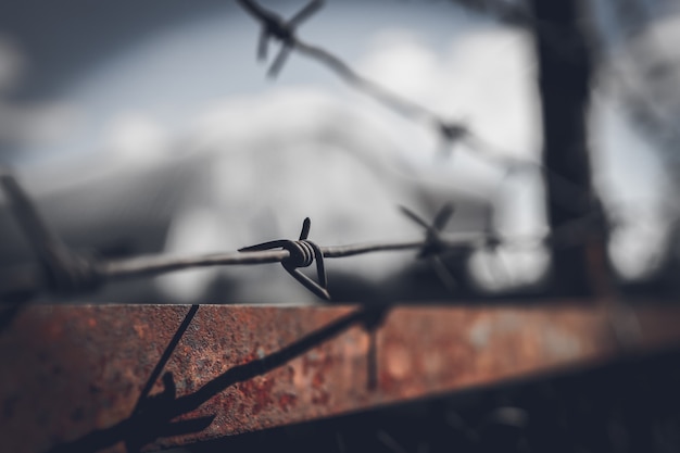 Photo barbed wire fence against dramatic, dark sky.