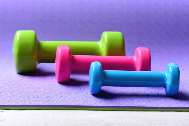 Barbells in small size, close up. Sports and healthy lifestyle concept. / Healthy shape and sport concept. Shaping and fitness equipment. Dumbbells made of ______ plastic on ______ background.