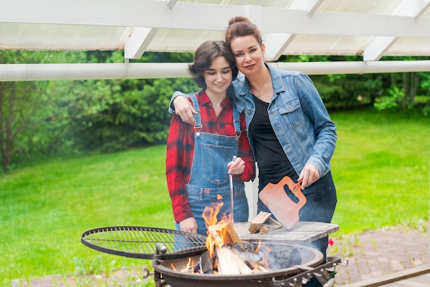 Barbeque party in garden with mom and her daughter at the grill in a country