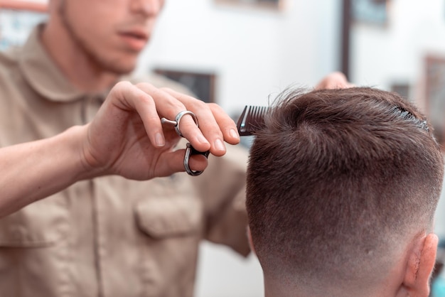 Barber in Barbershop shear hair electric car to young guy hipper for fashionable hairstyle.