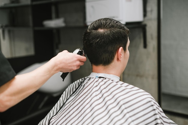 Barber clipping male brunette clipper rear view Work of a male hairdresser Copy space