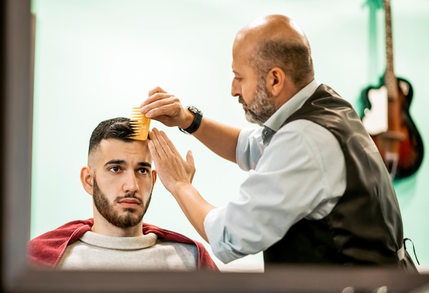 Barber combing clients hair in barbershop