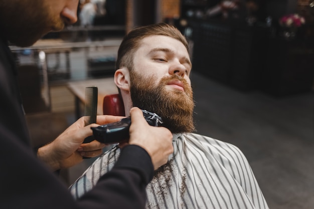 Barber cutting beard to a client