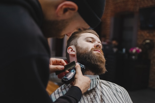 Barber cutting beard to a client